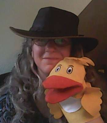 Image of the author wearing a hat and a duck glove puppet.
